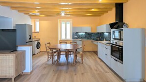 Kompakti keittiö, jossa on ruokapöytä, integroidut kodinkoneet ja pesukone.