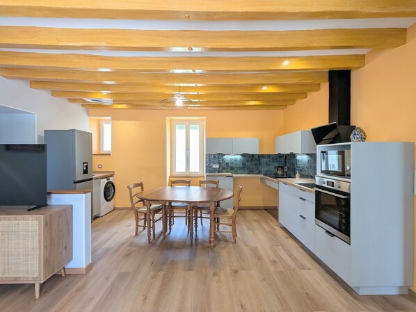 A compact kitchen with a dining table, built-in appliances, and a washing machine.