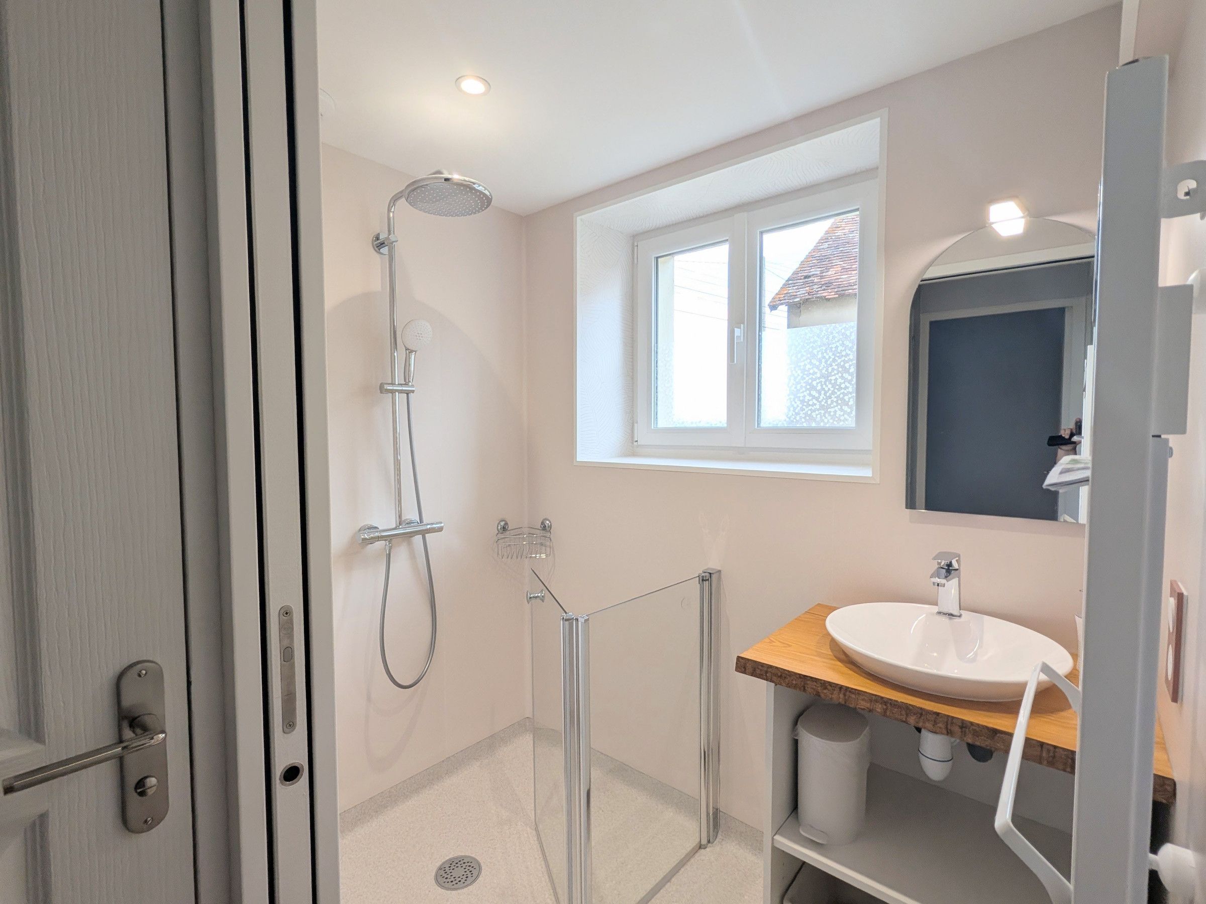 A modern bathroom with a shower, a sink, and a window providing natural light.