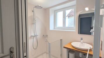 A modern bathroom with a shower, a sink, and a window providing natural light.