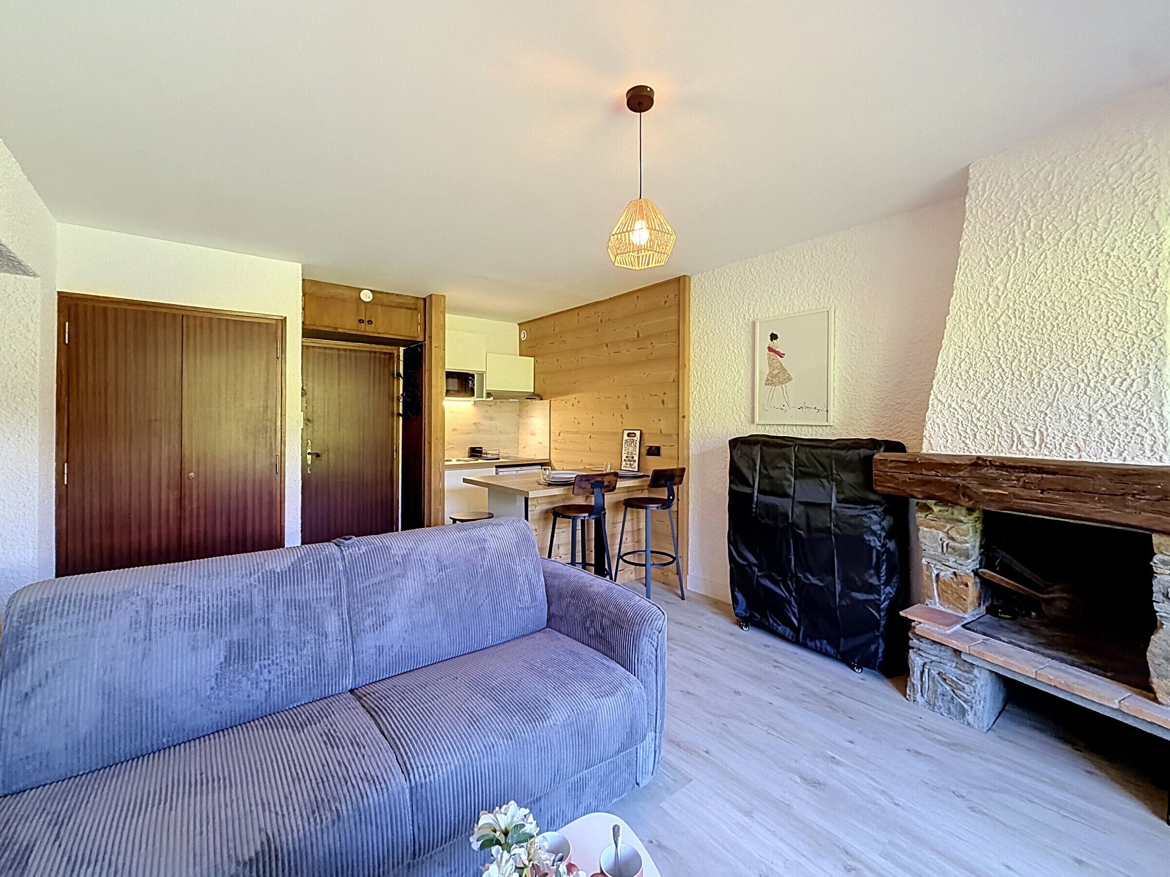 A living room with a sofa, a fireplace, and a kitchen in the background.