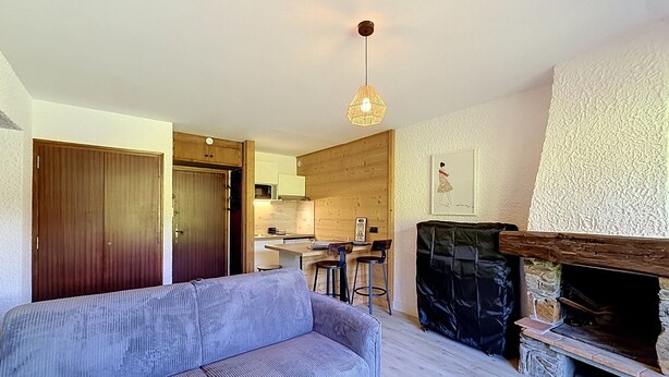 A living room with a sofa, a fireplace, and a kitchen in the background. - Studio at ski slopes, Mont Blanc view (Combloux)