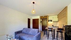 A compact living space with a sofa, a small dining table, and a kitchenette. - Studio at ski slopes, Mont Blanc view (Combloux)