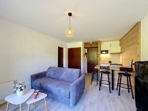 A compact living space with a sofa, a small dining table, and a kitchenette. - Studio at ski slopes, Mont Blanc view (Combloux)