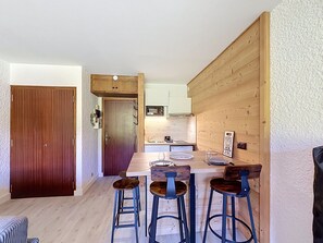 Una cucina compatta con mobili in legno, un tavolo da pranzo con quattro sgabelli e una porta ben visibile.