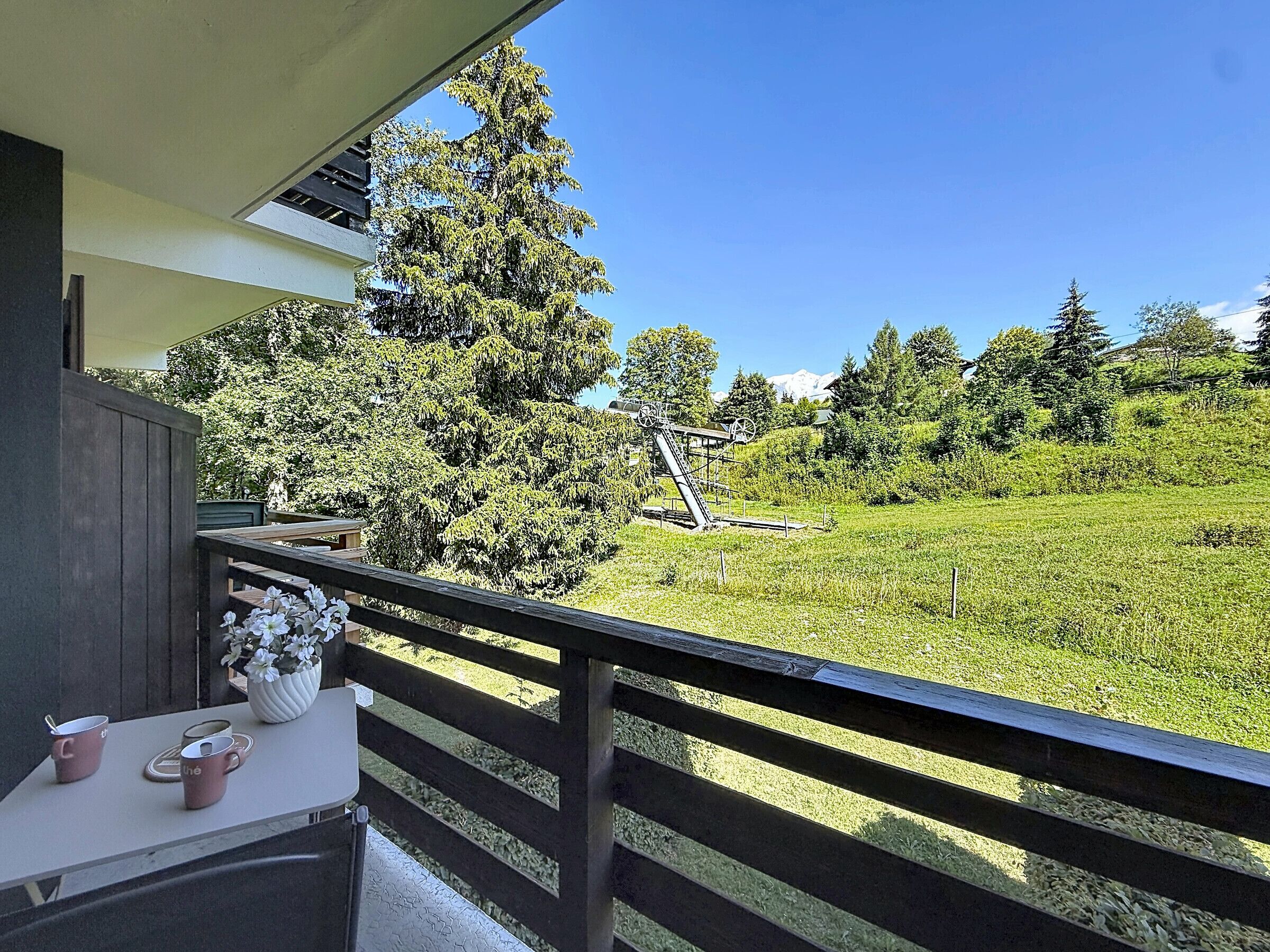 A balcony with a view of a green field and a windmill.