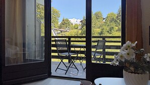 An open balcony with a table and chairs, a potted plant, and a red mug on the table. - Studio at ski slopes, Mont Blanc view (Combloux)