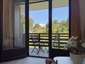 An open balcony with a table and chairs, a potted plant, and a red mug on the table. - Studio at ski slopes, Mont Blanc view (Combloux)
