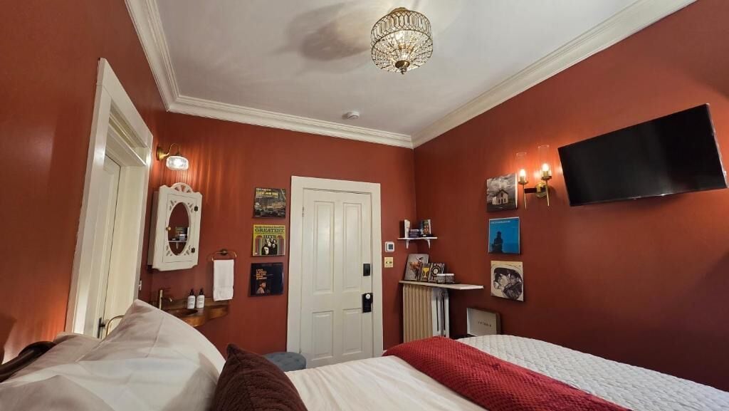 Quarto de hotel com uma cama, televisão na parede e uma porta.