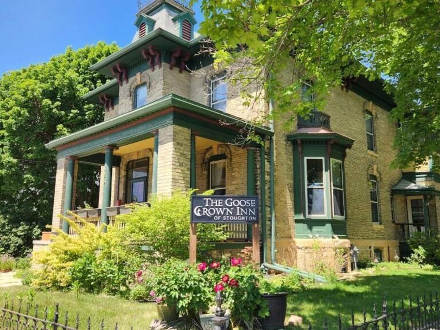 A two-story building with a green facade and a sign for 'The Goose Crown Inn of Stoughton.'