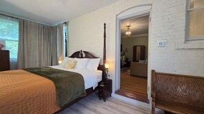 A bedroom with a four-poster bed, a nightstand, a wooden bench, and a doorway leading to another room. - The Goose Crown Inn of Stoughton (Stoughton)