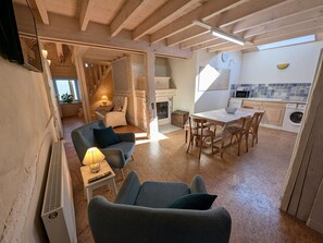 Ein gemütlicher Wohnbereich mit einer Couch, einem Esstisch und einer Küche im Hintergrund.