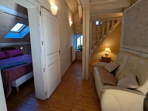 Una habitación acogedora con cama, sofá, escalera y tragaluz.