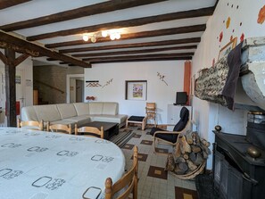 Een gezellige woonkamer met een bank, stoelen, een tafel en een open haard.