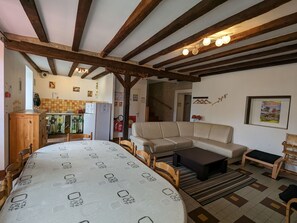 Una sala de estar acogedora con una mesa redonda, un sofá y un banco de madera. Cuenta con una zona de cocina con un refrigerador y un salpicadero de azulejos.