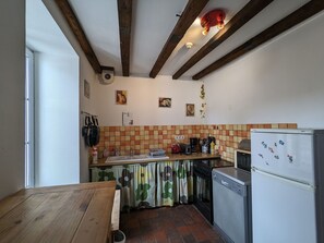 Un angolo cottura funzionale con un tavolo in legno, un frigorifero e una parete rivestita di piastrelle.