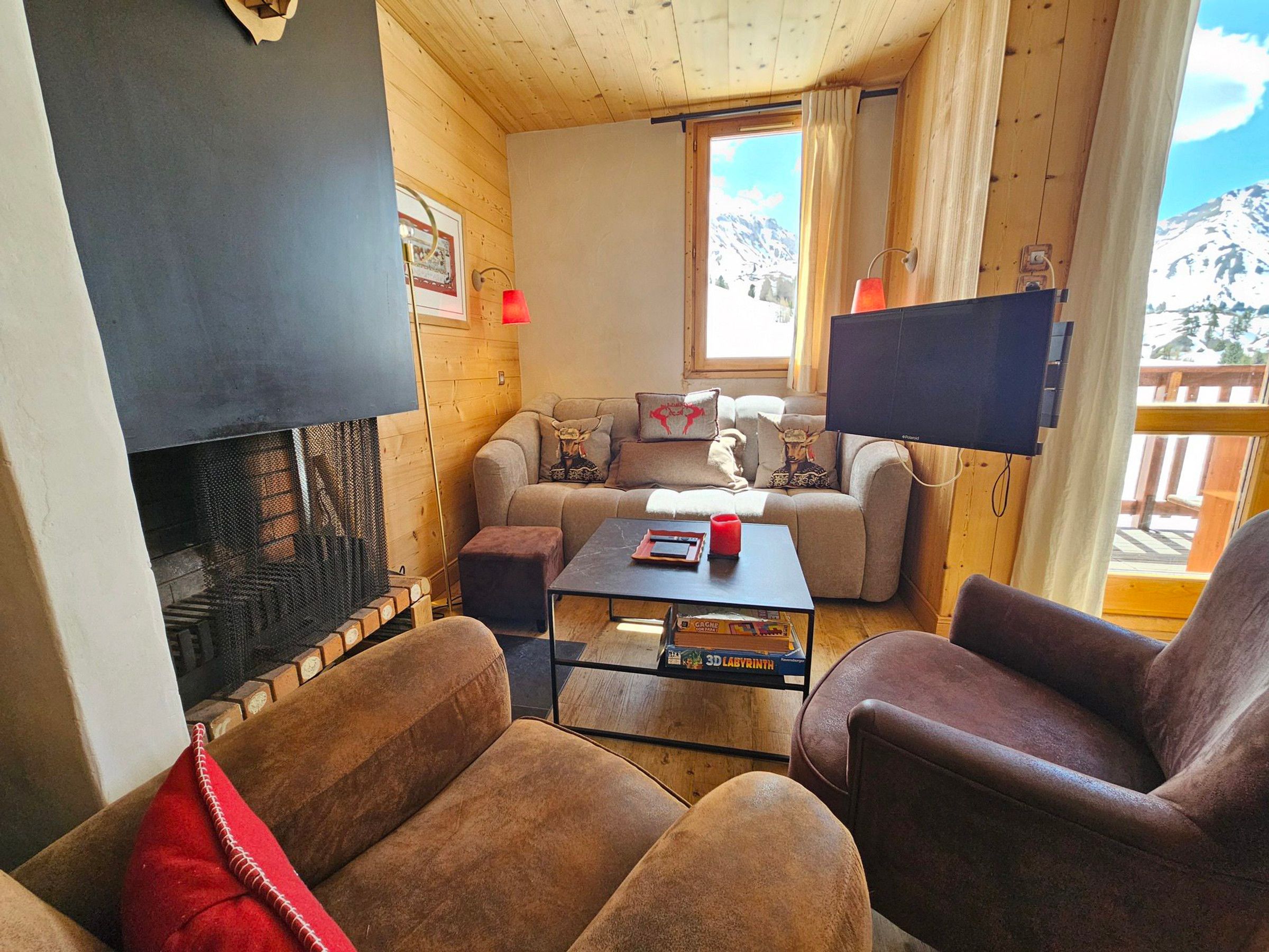 A cozy living room with a fireplace, a sofa, a coffee table, and a TV.