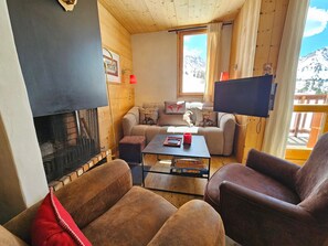 A cozy living room with a fireplace, a sofa, a coffee table, and a TV. - Cozy duplex, 6 guests, slope view (Plagne Villages)