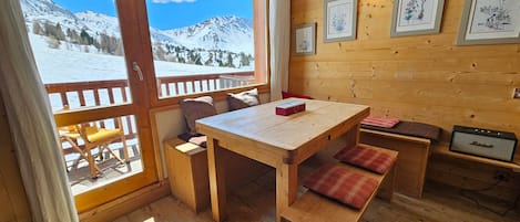 A wooden interior with a table, benches, and framed botanical prints on the wall.
