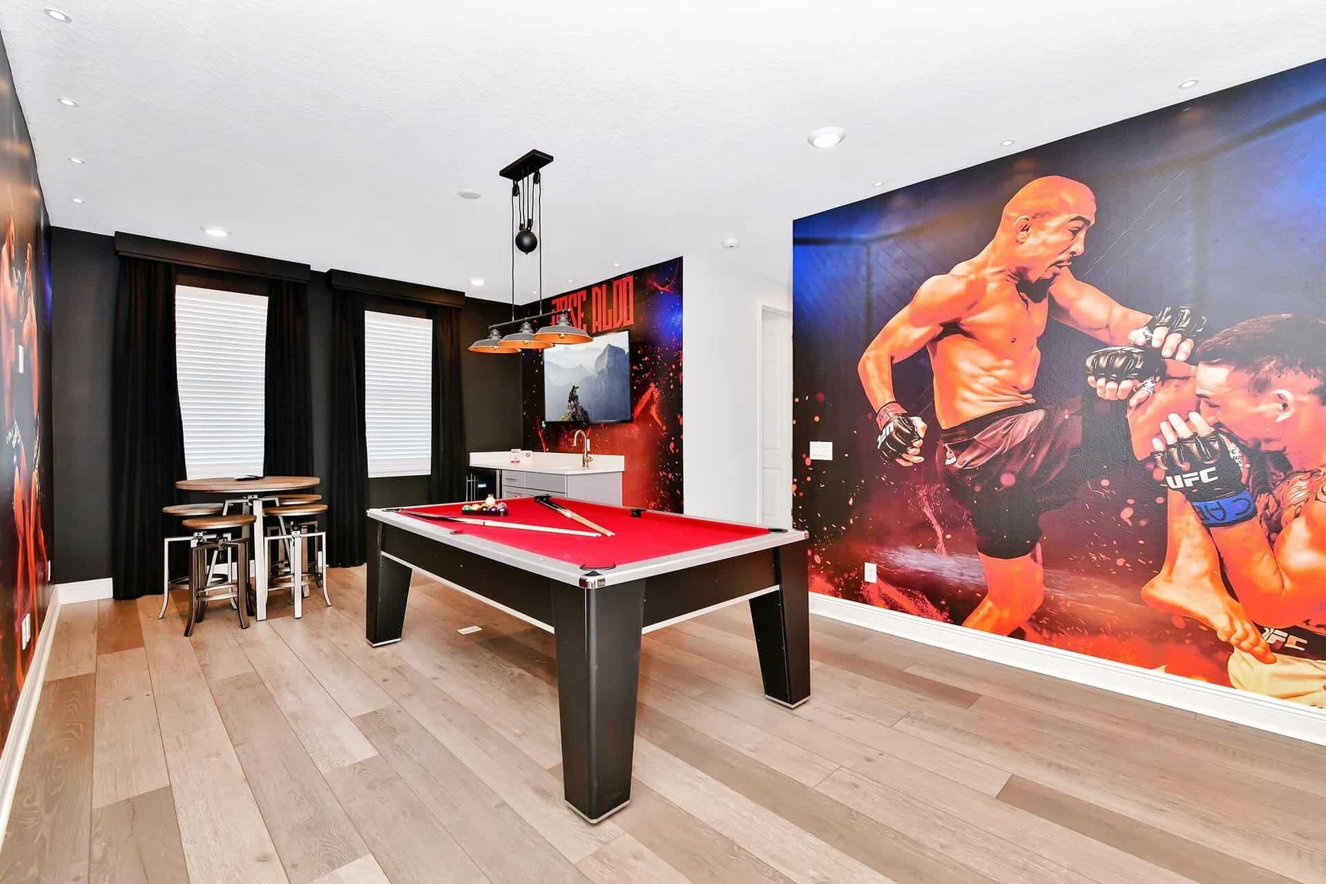 Una habitación con mesa de billar, zona de bar y un gran mural de un combate de boxeo.