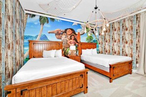 Ein Schlafzimmer mit zwei hölzernen Betten, einer Wandmalerei mit tropischer Szene und einem Kronleuchter.