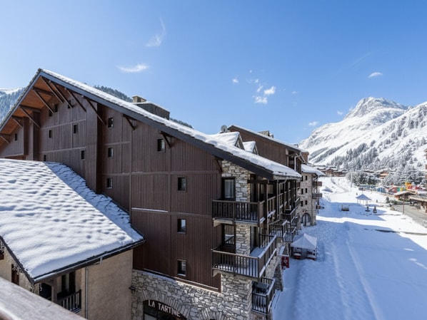 Un edificio de madera de varios pisos con detalles de piedra, balcones y un techo cubierto de nieve.