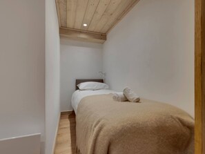A small, narrow room with a single bed, a wooden ceiling, and white walls. - Charming and spacious duplex apartment - 7 guests (Val-d'Isère)