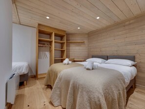 A wooden-paneled room with two beds, a wooden wardrobe, and a bench. - Charming and spacious duplex apartment - 7 guests (Val-d'Isère)