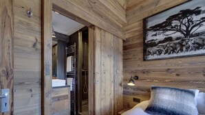 A wooden-paneled bedroom with a bed, a painting of a tree, and a shower area. - Chalet apartment, central quiet area - 8 guests (Val-d'Isère)