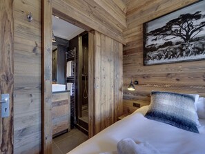 Ein Schlafzimmer mit Holzwänden, einem Bett, einem Baumgemälde und einer Dusche.