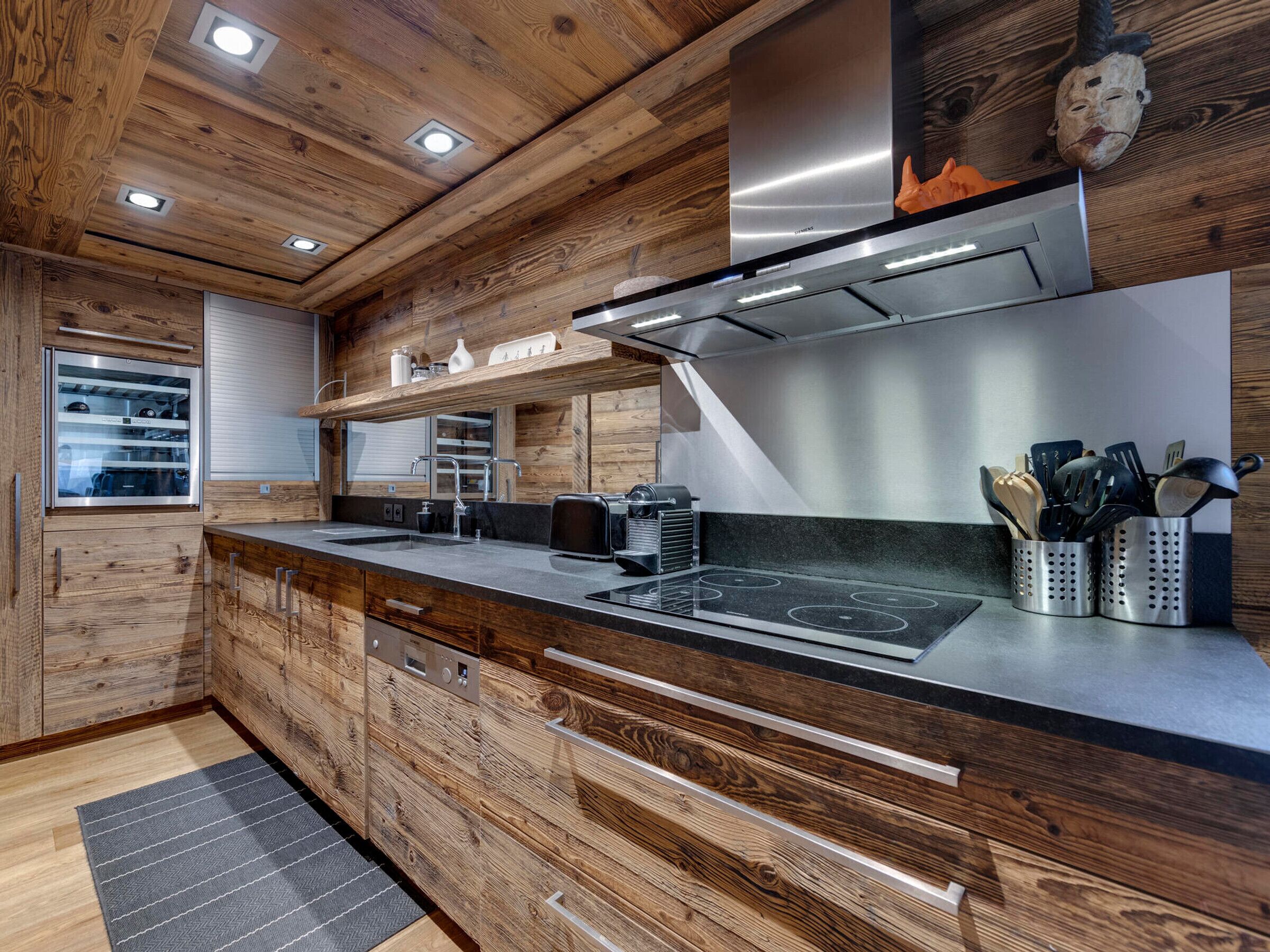 Una cocina moderna con armarios de madera, una campana extractora de acero inoxidable y un horno empotrado.