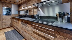 A modern kitchen with wooden cabinetry, a stainless steel range hood, and a built-in oven. - Chalet apartment, central quiet area - 8 guests (Val-d'Isère)