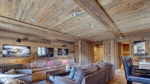 A cozy cabin interior with a wooden ceiling, a sofa, a dining table, and artwork on the walls. - Chalet apartment, central quiet area - 8 guests (Val-d'Isère)