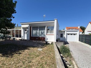 Ein einstöckiges Haus mit Veranda, Garage und einem kleinen Garten.