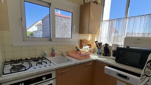 Eine kleine Küche mit Gaskochfeld, Backofen, Spüle und Mikrowelle.