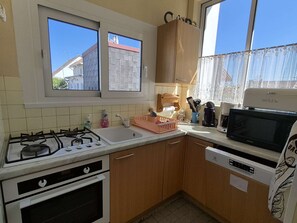 Eine kleine Küche mit Gaskochfeld, Backofen, Spüle und Mikrowelle.