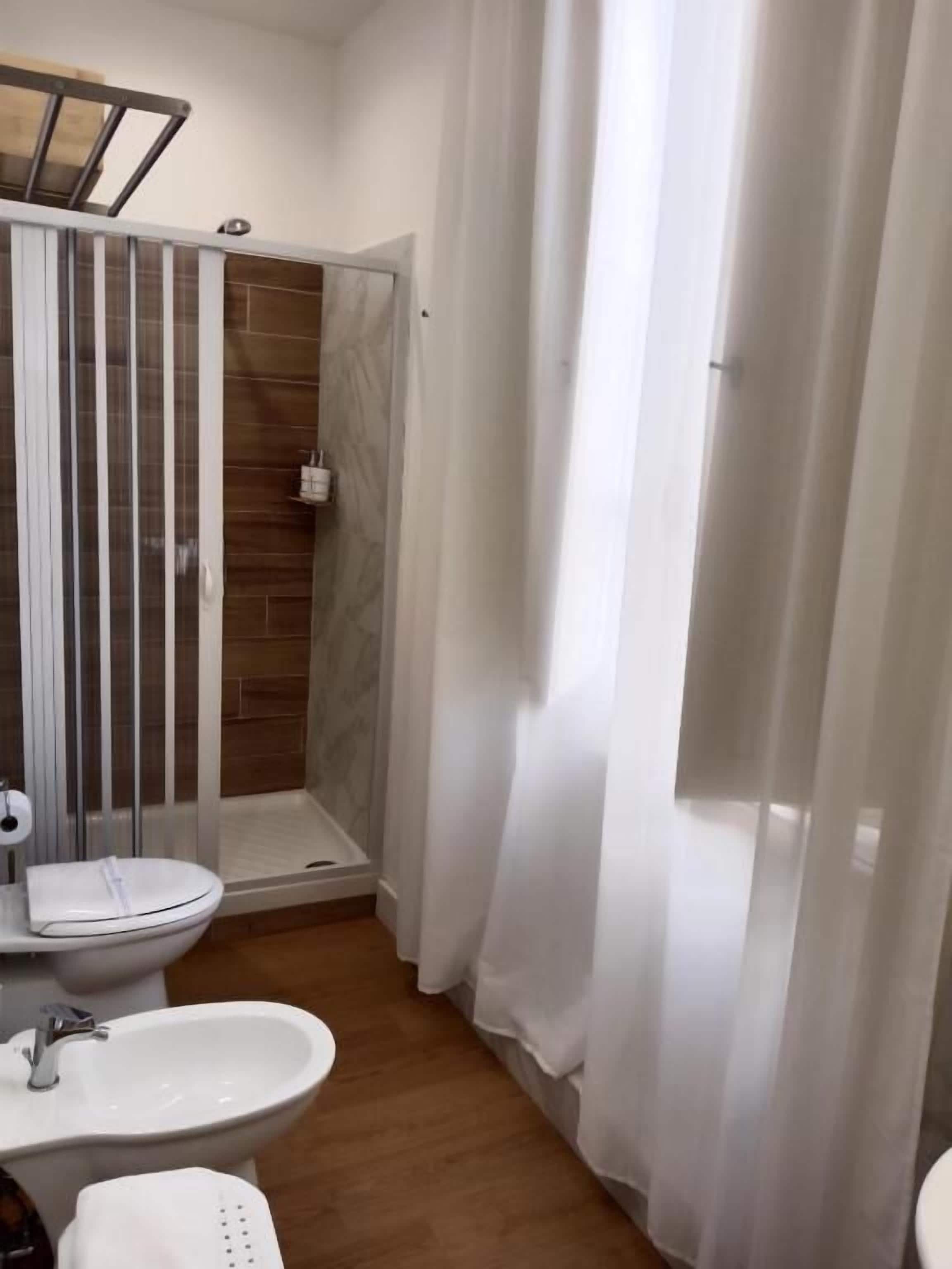 Une salle de bain avec douche, toilettes et bidet.