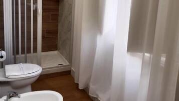 Une salle de bain avec douche, toilettes et bidet.