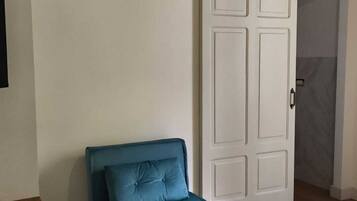 Une pièce avec un canapé bleu, une porte blanche et un plancher en bois.