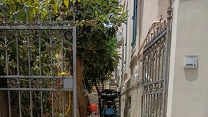 En smal gyde med et metalhegn, et træ og en parkeret motorcykel.