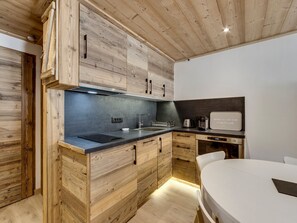 Cuina moderna amb armaris de fusta, taulell negre i forn integrat.