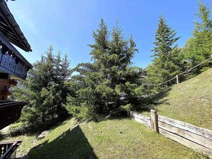 A building with a sloped roof and a wooden deck. - Charming apartment - 4 guests, forest view (Méribel)