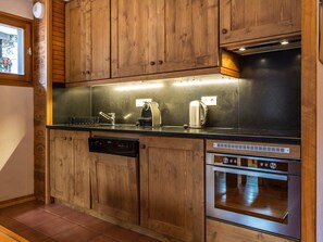 A modern kitchen with wooden cabinets, stainless steel appliances, and a built-in oven. - Convenient apartment at ski slopes - 4 guests (Val-d'Isère)