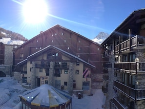 A large wooden building with multiple balconies and a stone facade, surrounded by snow. - Convenient apartment at ski slopes - 4 guests (Val-d'Isère)