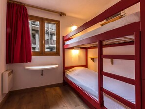 A small, compact room with a bunk bed, a window with curtains, a bedside table, and a radiator. - Convenient apartment at ski slopes - 4 guests (Val-d'Isère)
