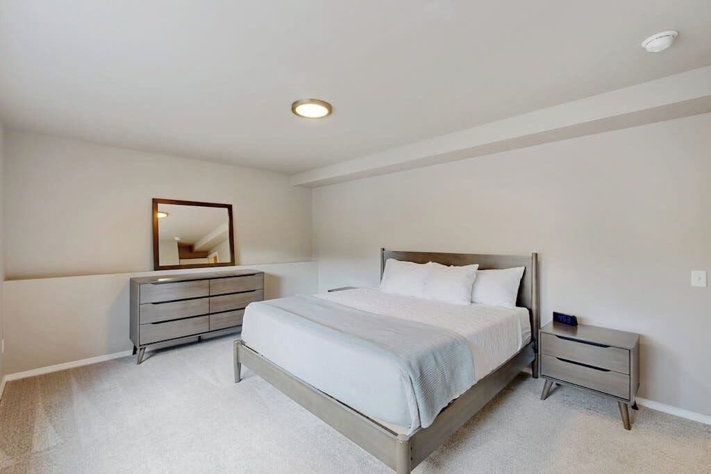 A bedroom with a bed, a dresser, a nightstand, and a mirror.
