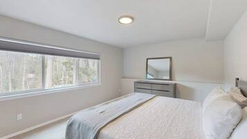 A bedroom with a bed, a dresser, a mirror, and a window.