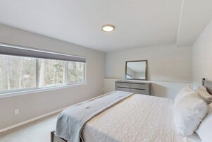 Un dormitorio con cama, cómoda, espejo y ventana.