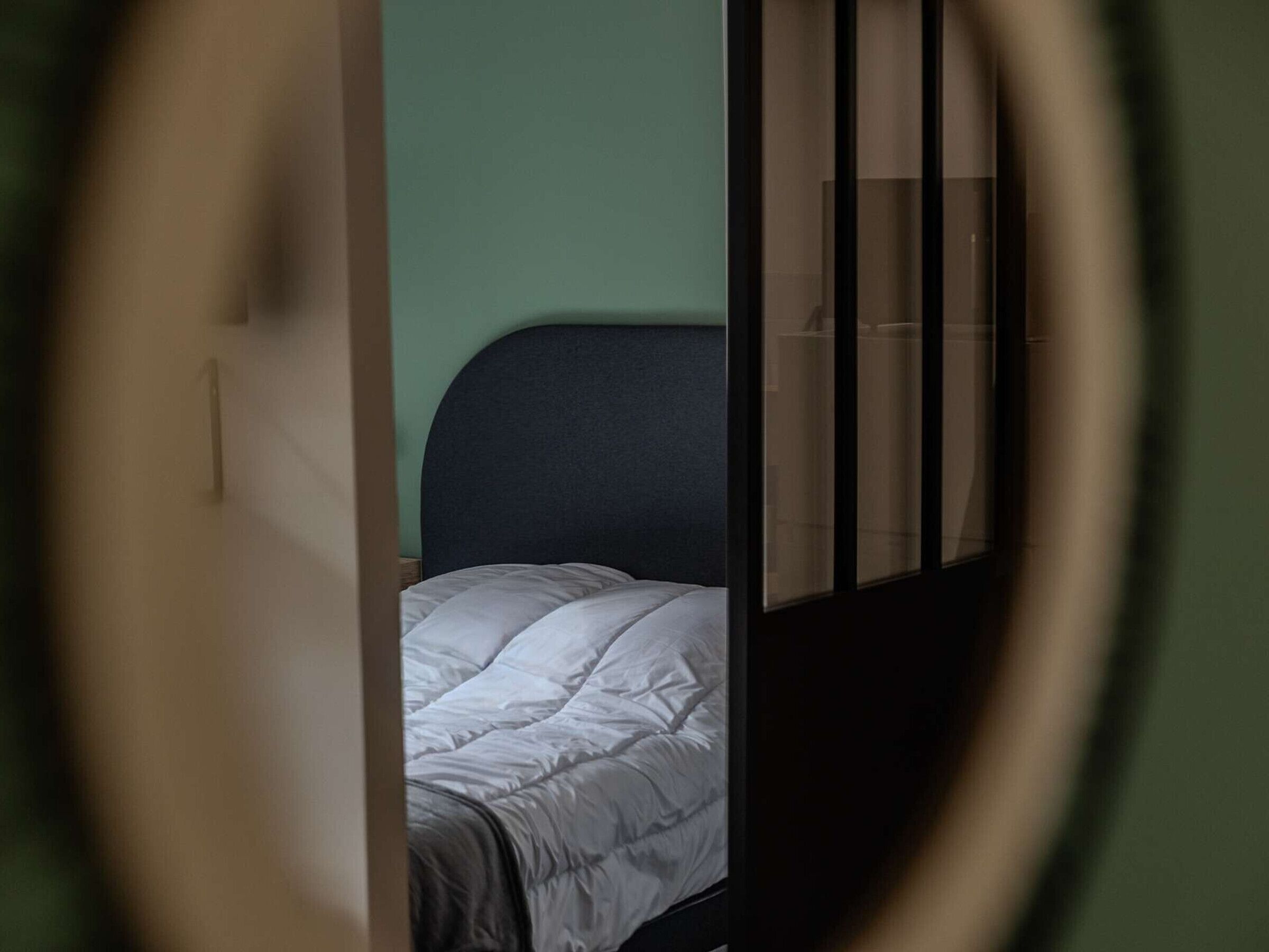 A room with a bed, a window with blinds, and a partial view of a door.