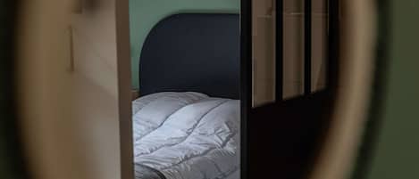 A room with a bed, a window with blinds, and a partial view of a door.